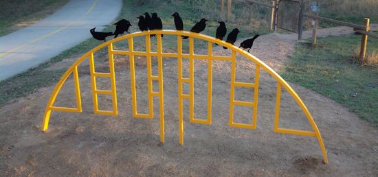 Yellow bike rack with bird cut outs sitting on top.