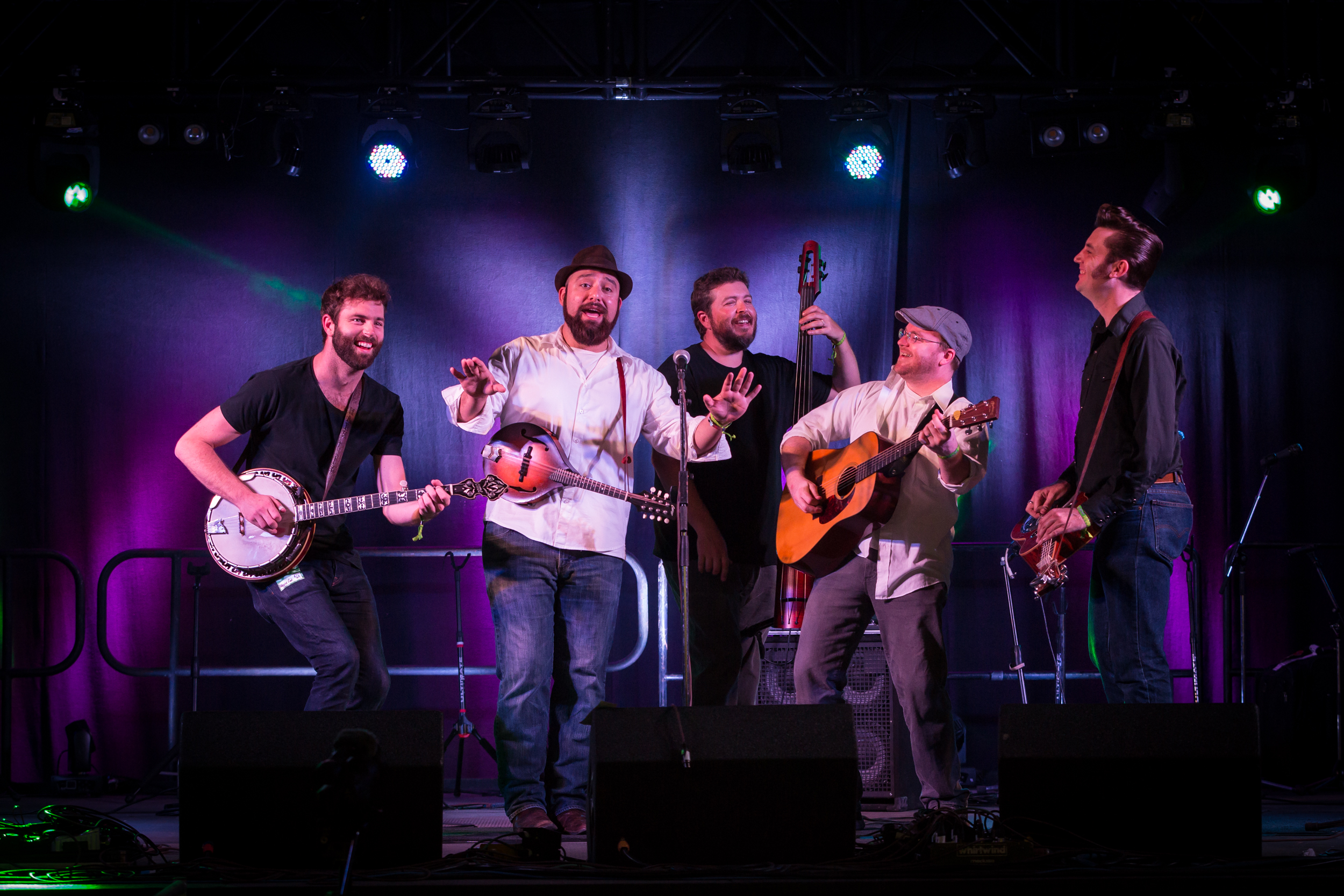 The Hillbenders singing on a stage with a purple backdrop.