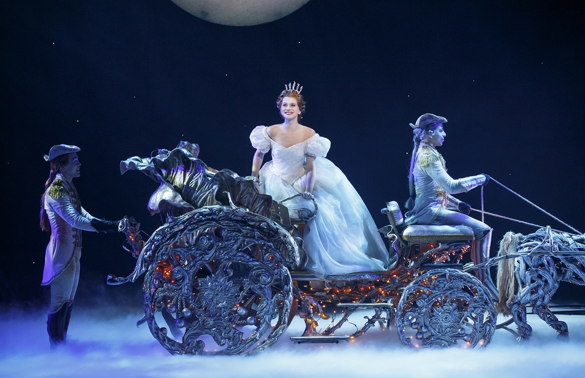 Cinderella smiling while she sits in the pumpkin carriage.