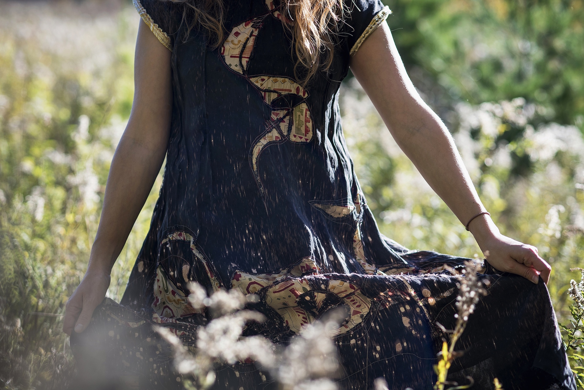 A photo of a handmaid dress. It is dark blue with graphic embroidery.