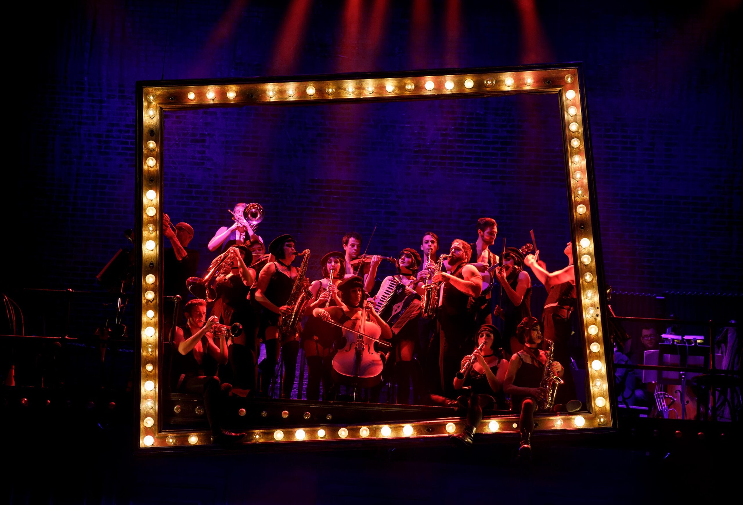 The band of Cabaret playing while sitting on a lighted frame.