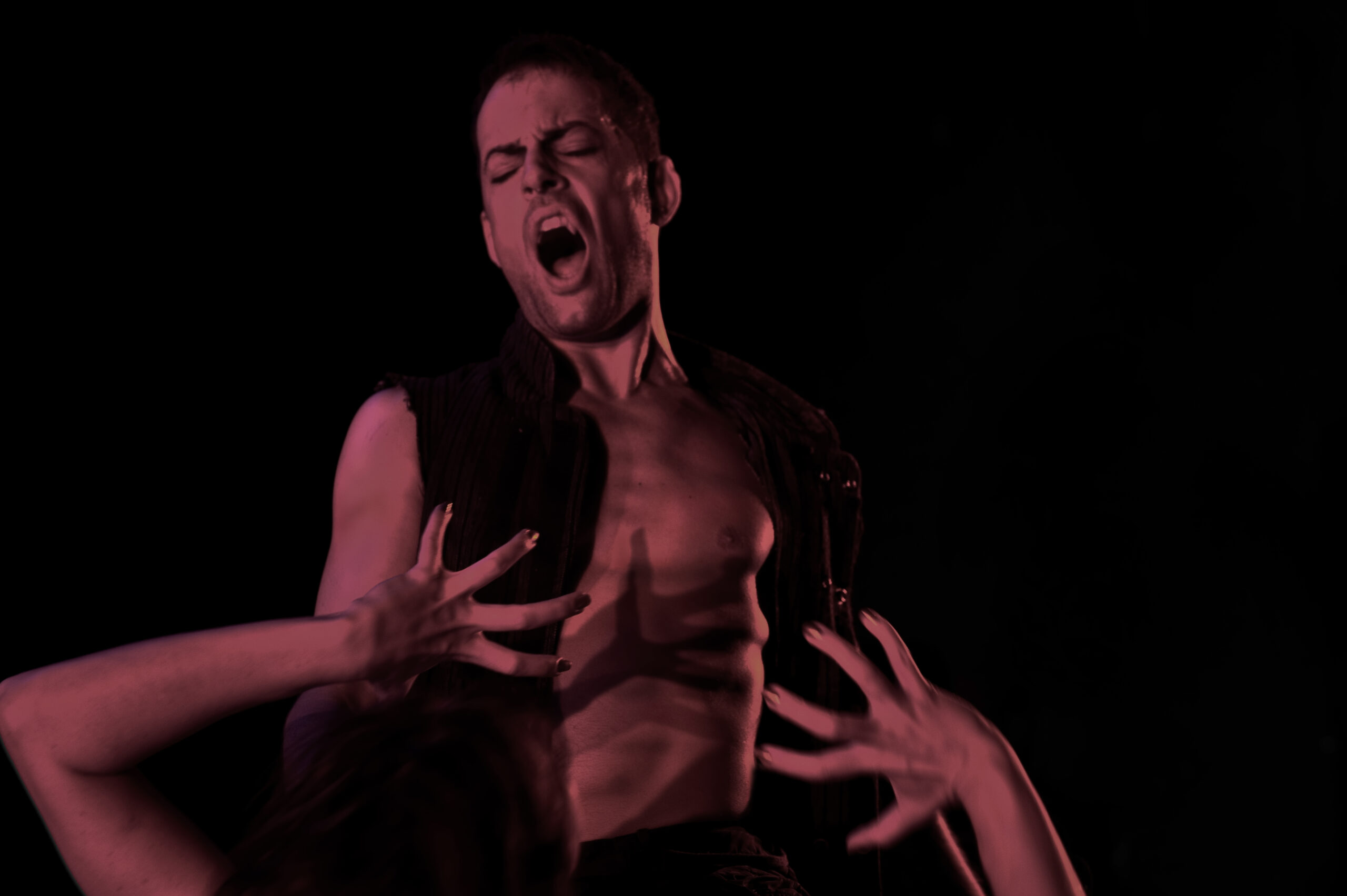 A shirtless Dracula with his mouth open and eyes closed. Hands reach up for his bare chest.