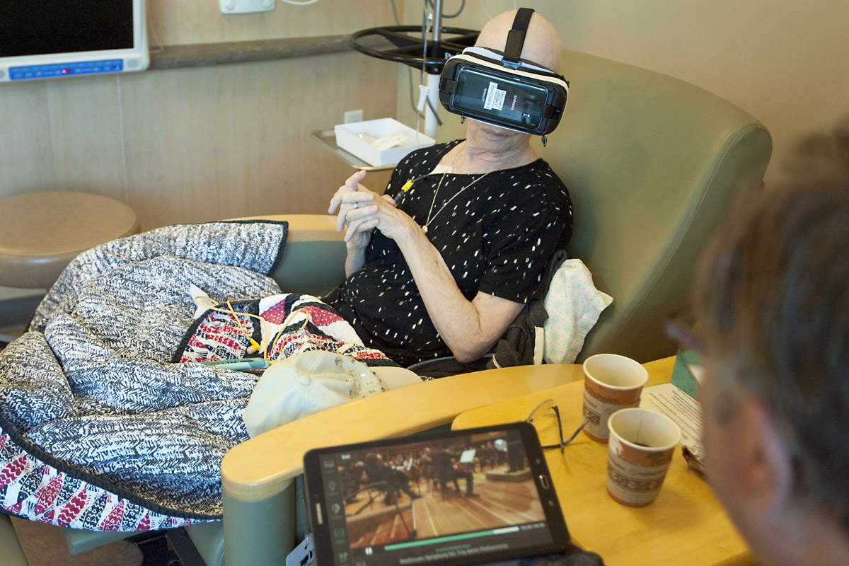 During chemotherapy, Mary Hill watches a short virtual reality video that puts her in her favorite seat at a symphony – right next to the violinists – while her husband, John Hill, watches on a tablet. Photos by Joel Blocker, for UCHealth.