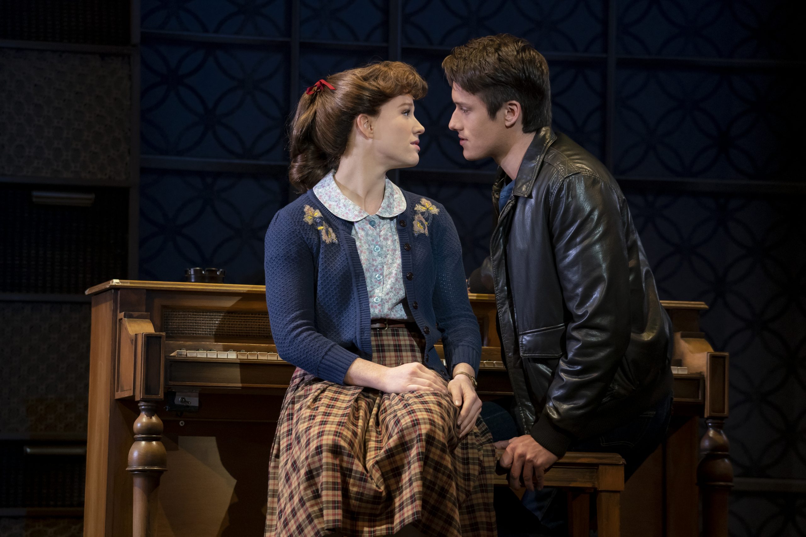 Carol King and Gerry Goffin about to kiss on a piano bench