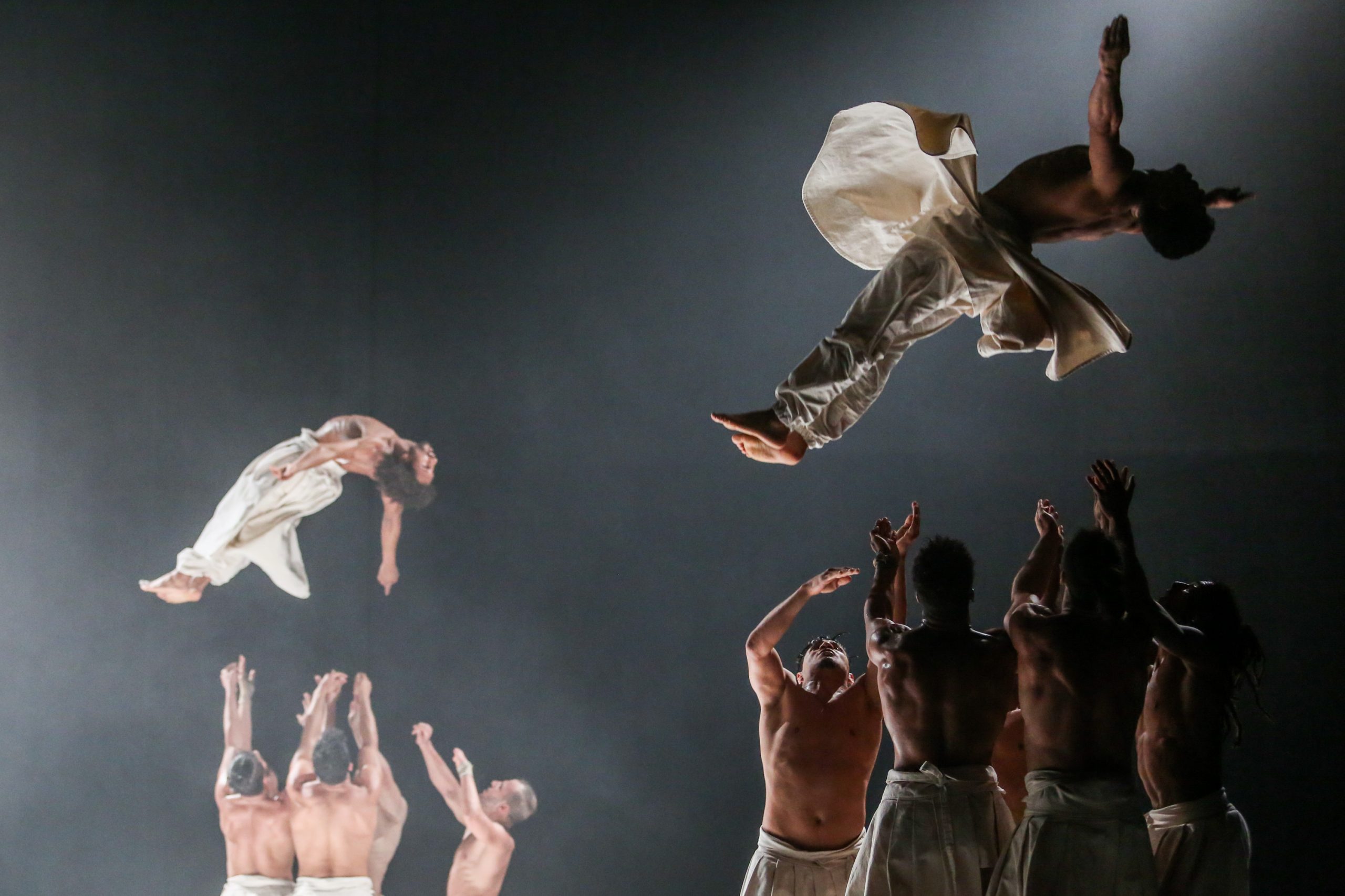 Cie Herve Koubi dancers thrown into the air wearing traditional Morccan garb.