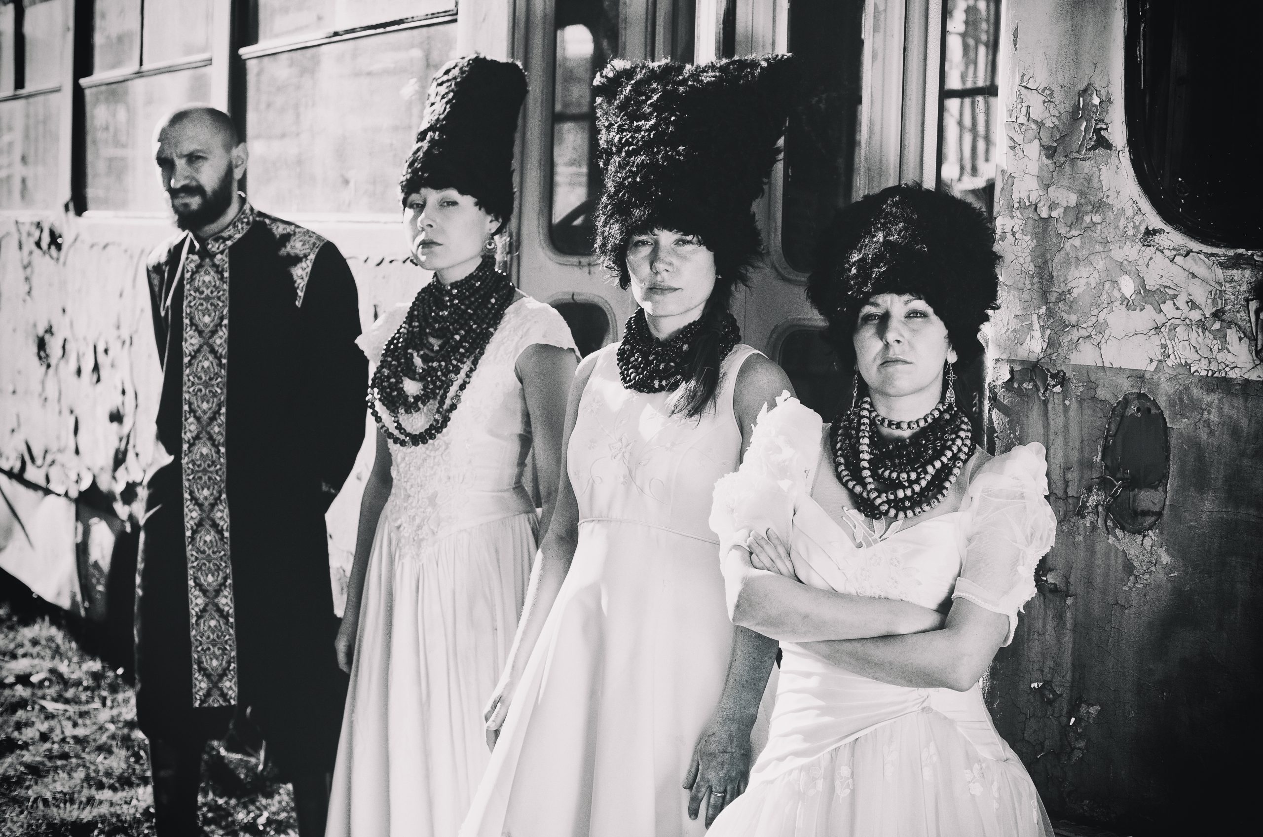 The members of Dakha Brakha wearing traditional Ukrainian garbs staring at the camera seriously. The photo is black and white.