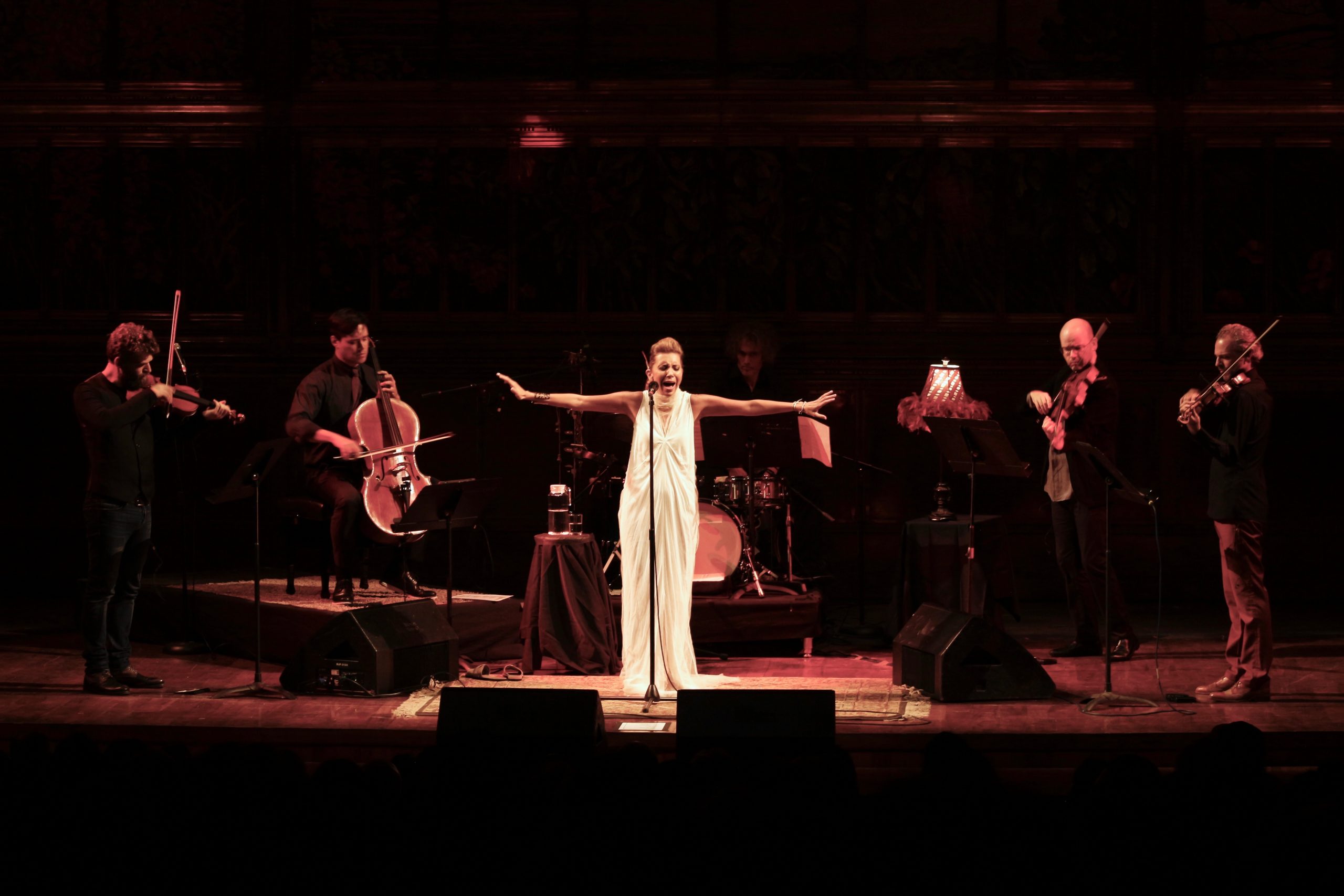 Photo of Magos Herrera singing on stage with her arms outstretched.