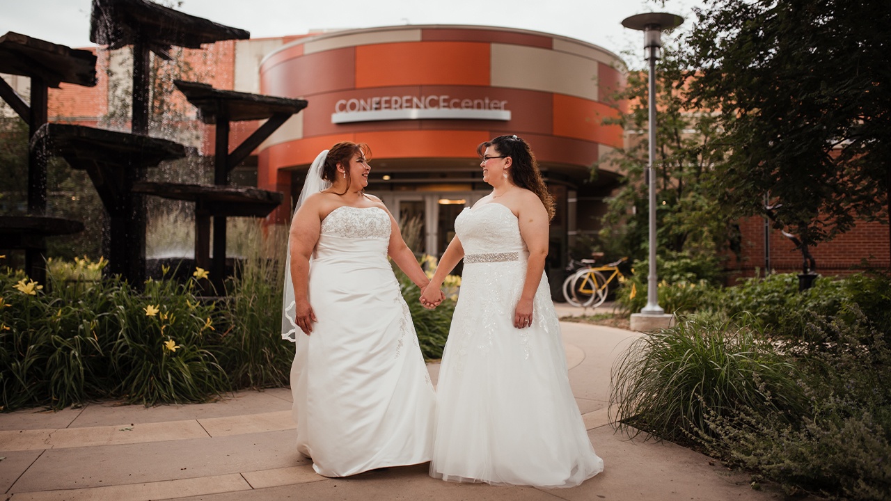 Beautiful brides stand outside of The Lincoln Center in front of the fountain.