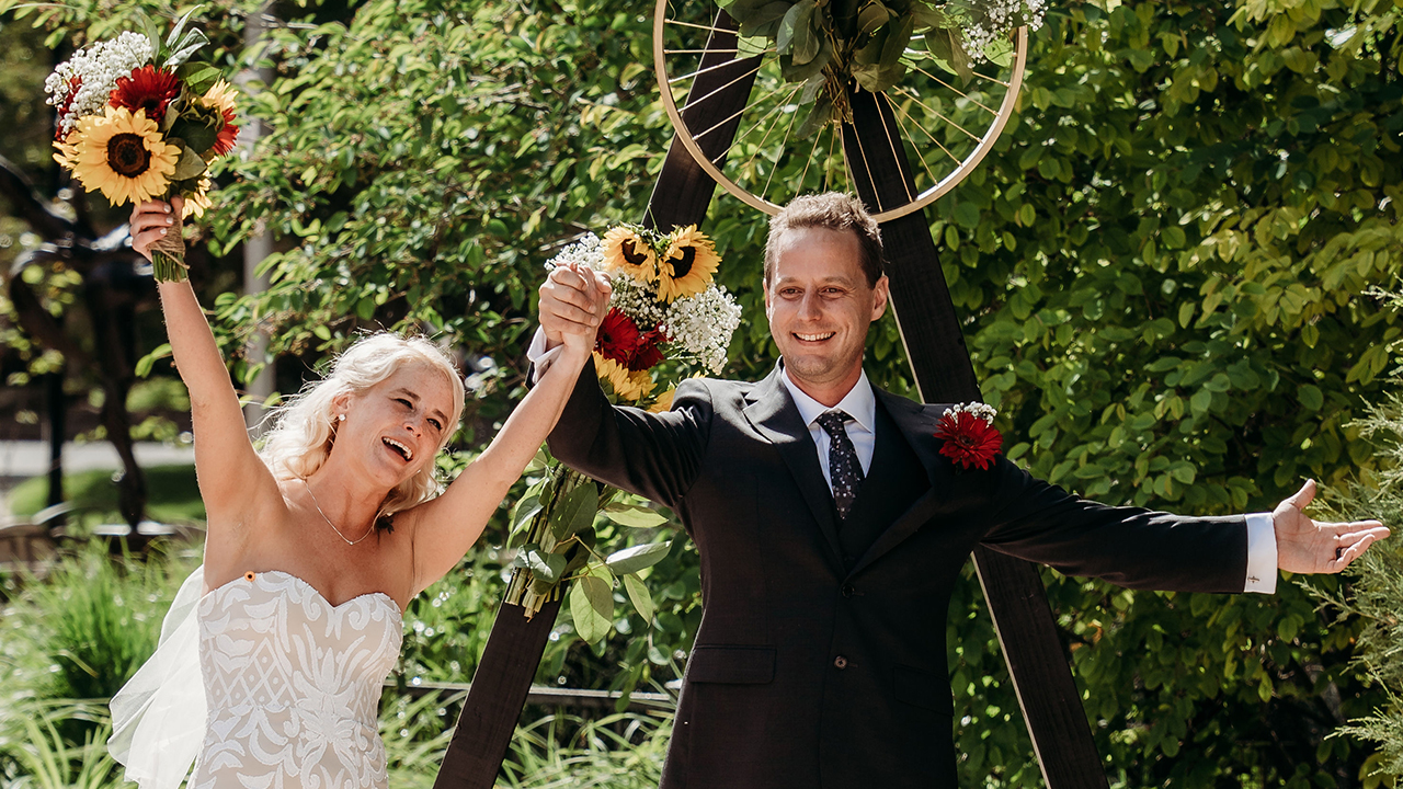 Bride and groom raising their slasped hands in triumph and smiling