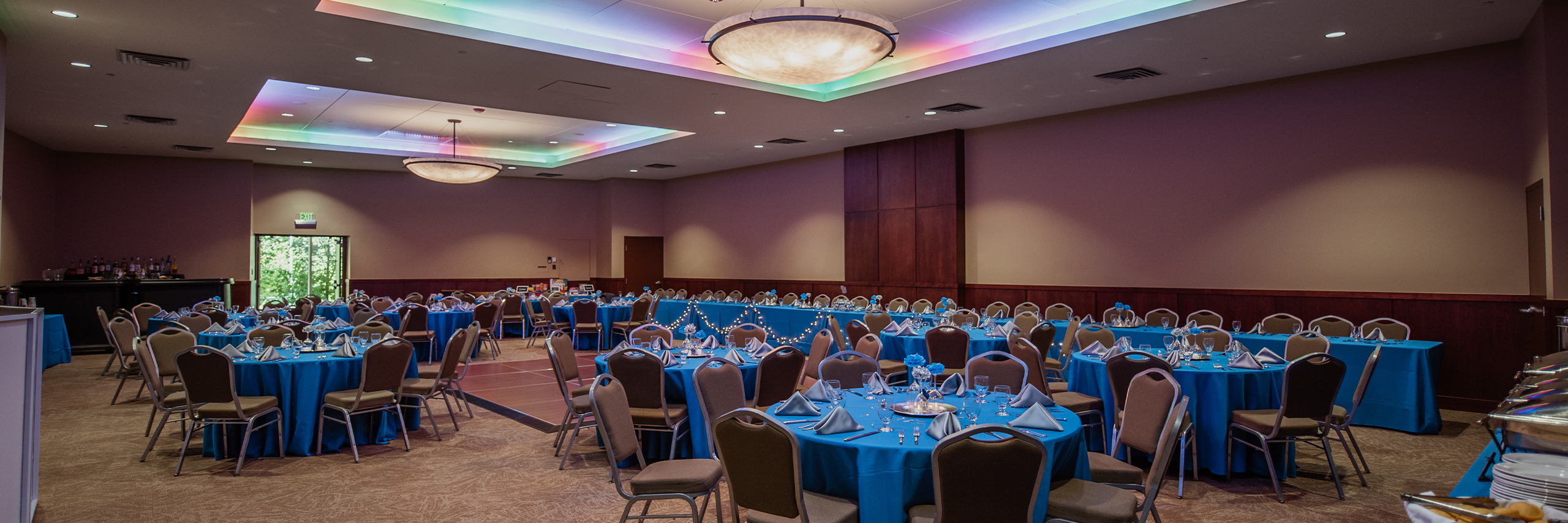 Photo of Columbine Room set up for a reception with colorful lights and blue tablecloths.