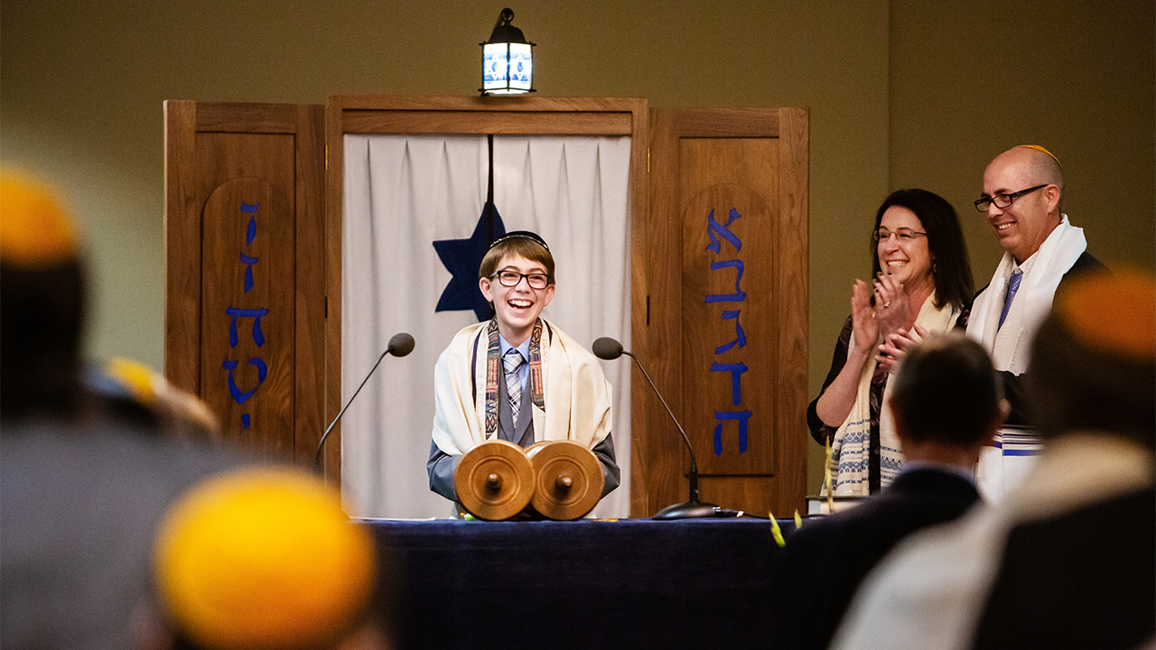 A boy and his parents stand at his Bar Mitzvah altar.