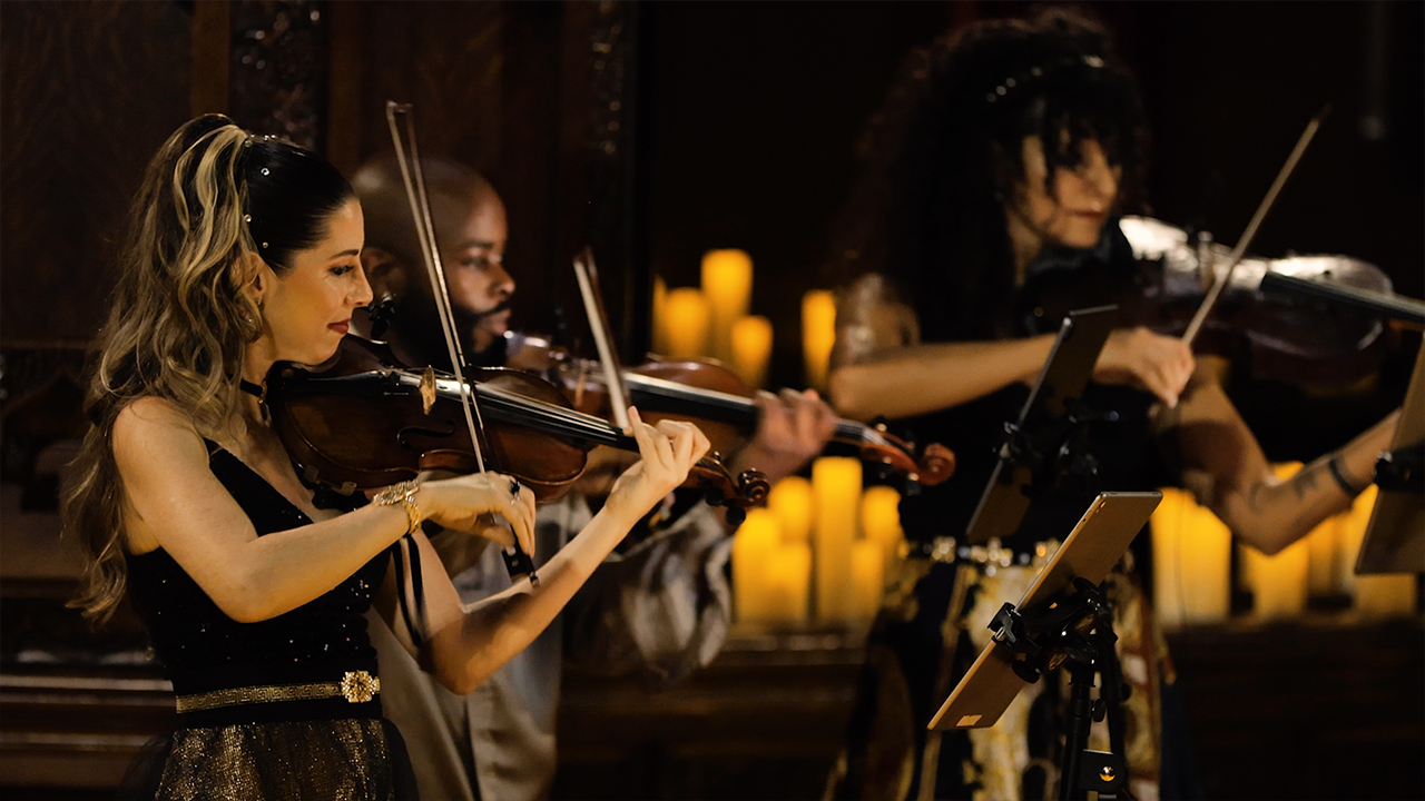 The members of Vitamin String Quartet playing amongst candles.