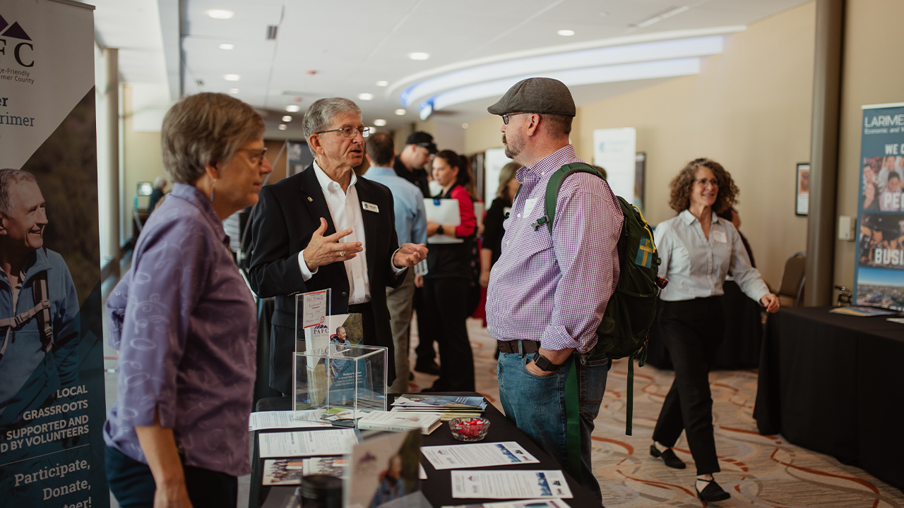 Expo attendees speak to conference attendees in the Columbine Room lobby.