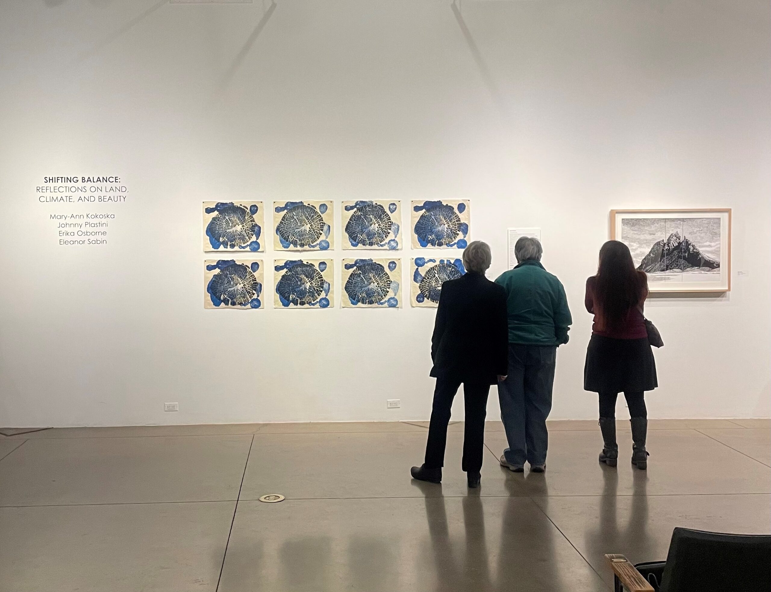 Three patrons looking at an exhibit on the wall.