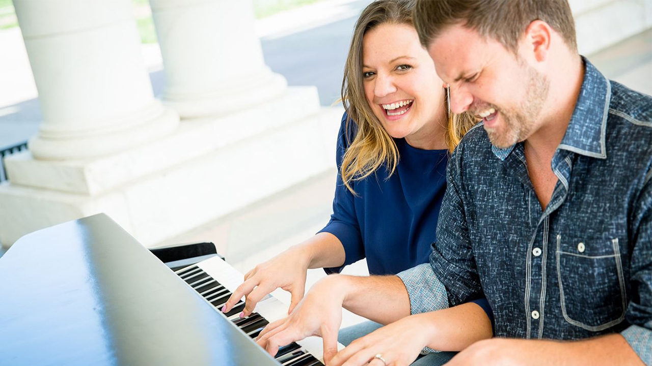 Happy couple playing the piano together.