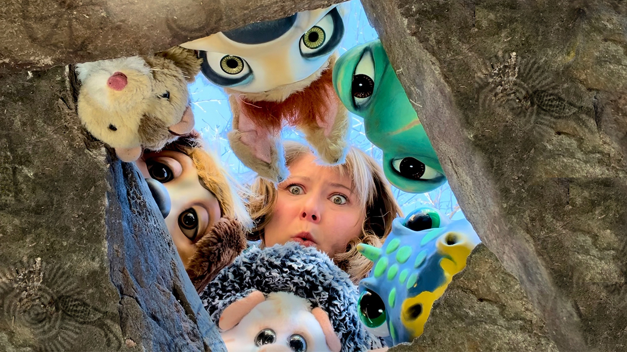 Puppeteer Meghan Casey and her puppets peer through a hole in the ground