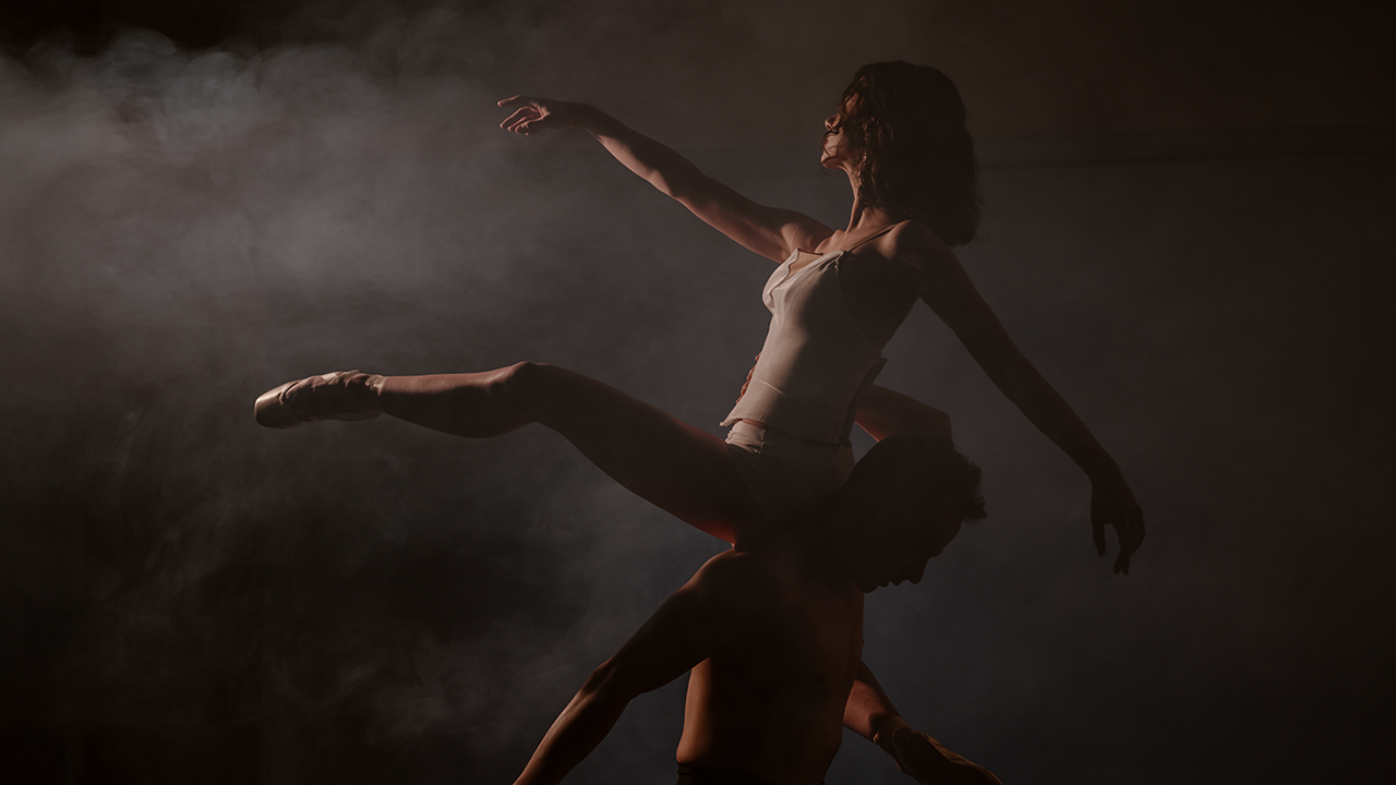 Two ballet dancers dancing on a dark misty stage
