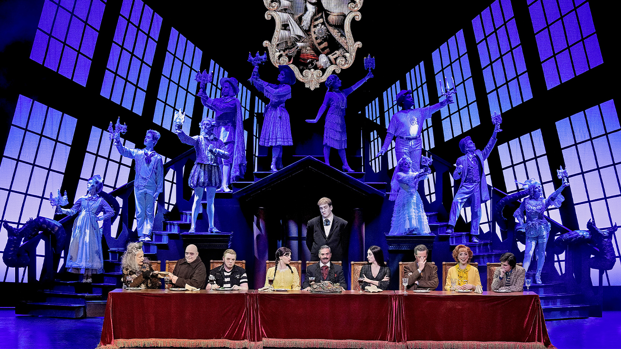 The Addams Family members sit at a long table, resembling the painting "The Last Supper"