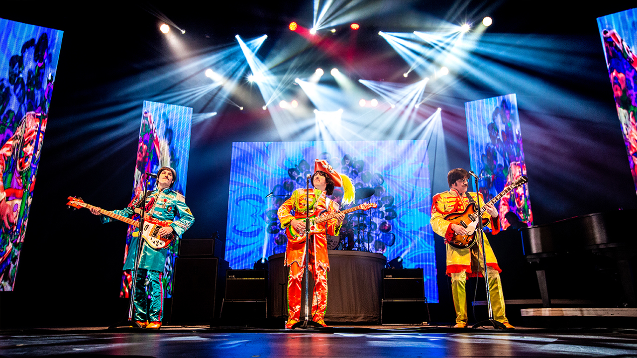 Members of RAIN perform on stage in the classic colorful Beatles Sgt. Pepper outfits