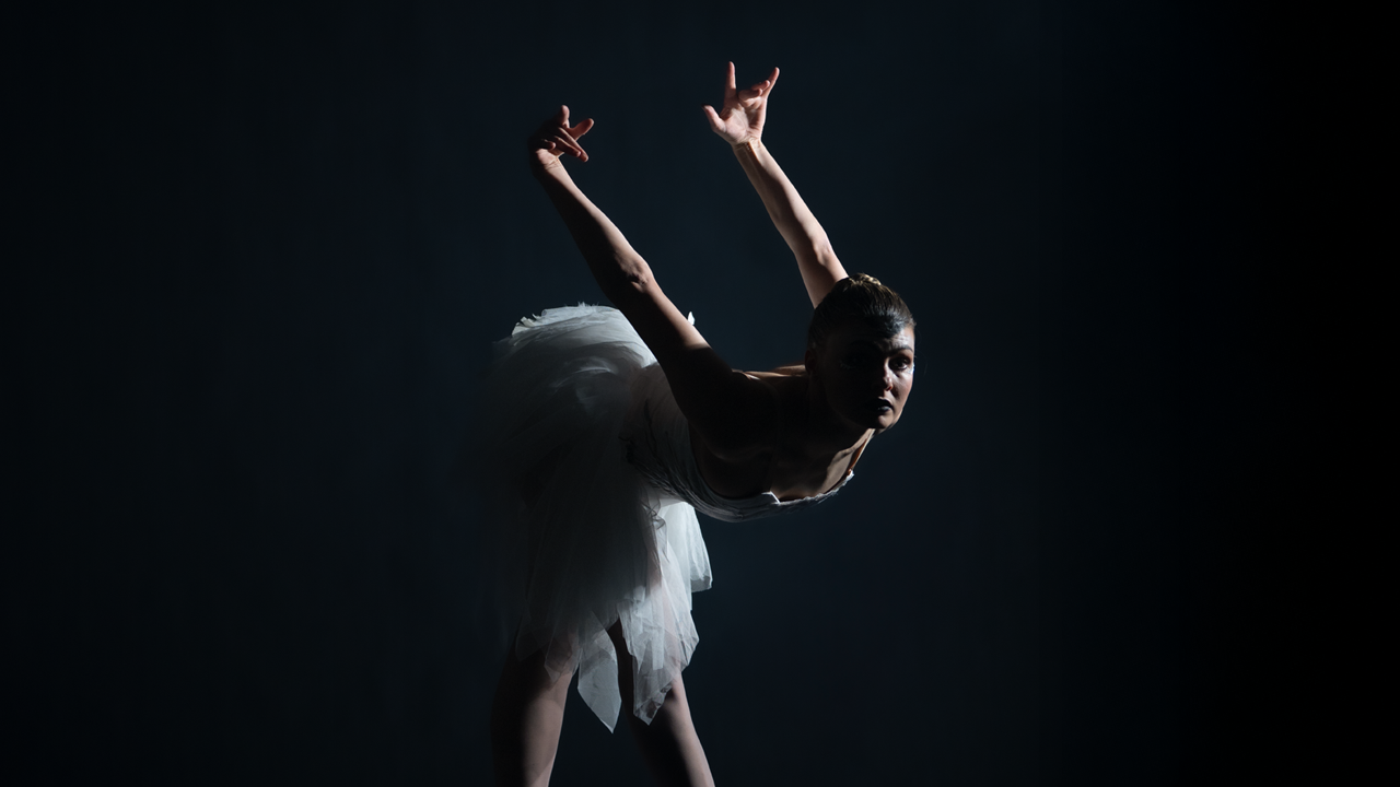 Ballet dancer dressed as a swan doing a swan dive on stage