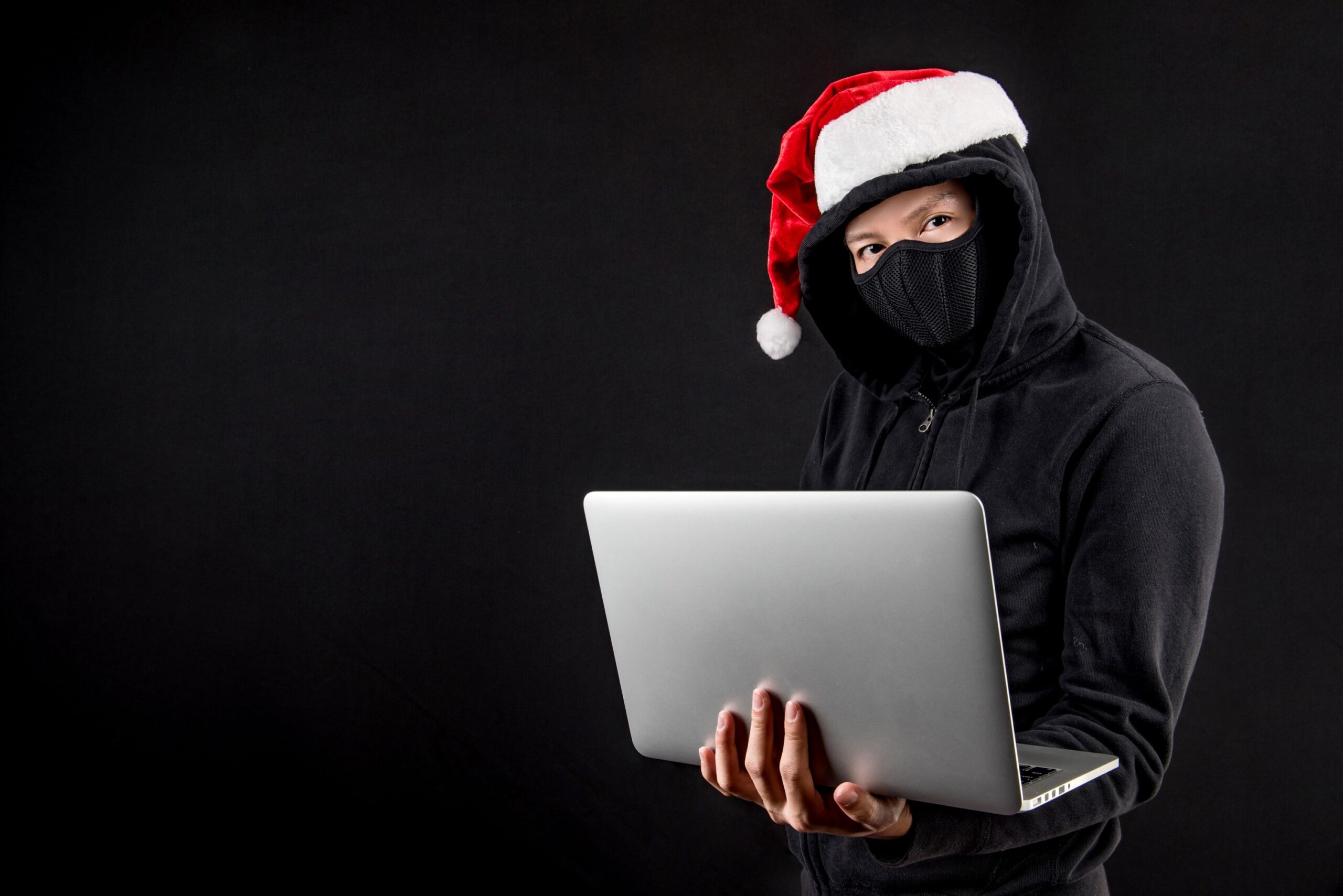 mysterious male santa hacker holding laptop computer