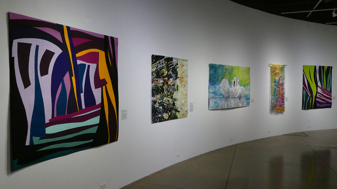 5 Quilts hanging on a gallery wall