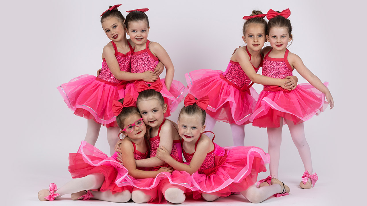 Group of tiny dancers dressed in pink, hugging