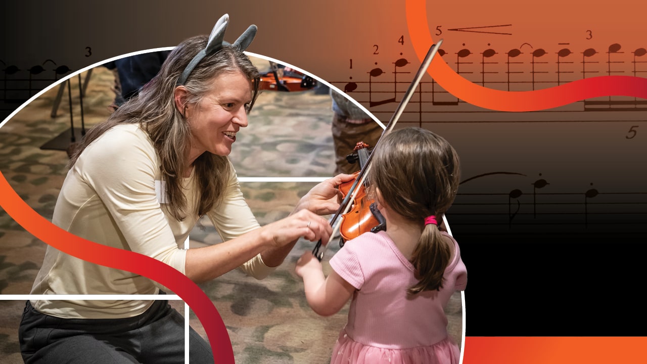 A woman kneels on the floor to show a young child how to hold a violin