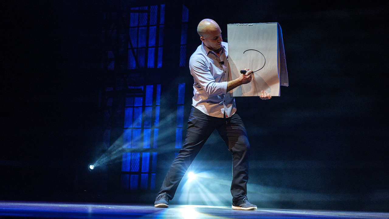 Bill Blagg on stage drawing a circle on a large note pad