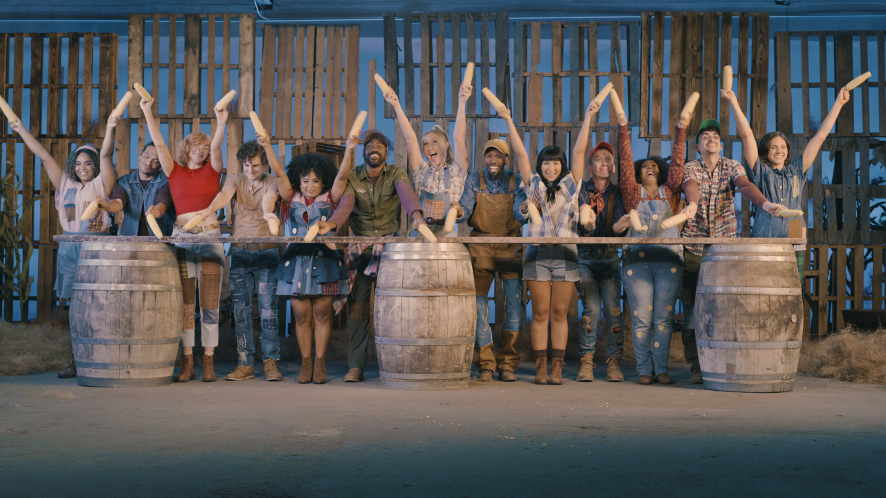 The cast holding corn on the cobs up in the air