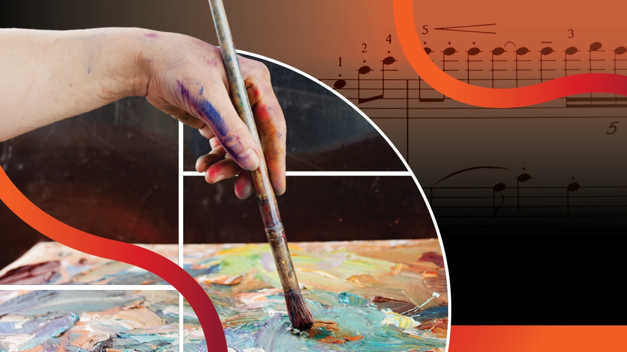 An artist's hand dips a paintbrush onto a canvas with abstract streaks of multiple colors,