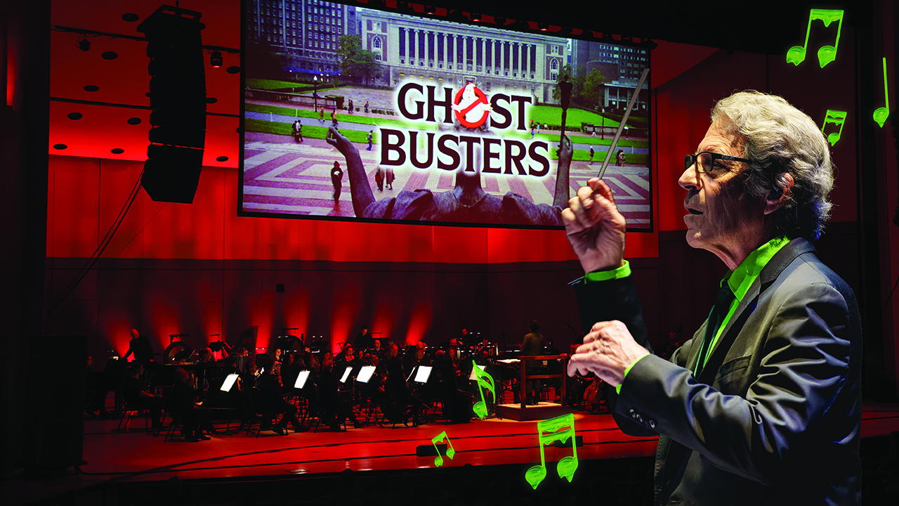 Conductor holding baton with an orchestra on stage. A big screen is above the orchestra displays the Ghostbusters movie.